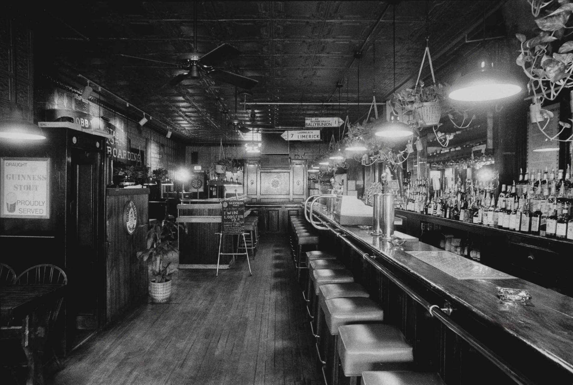 Black-and-white interior of the Beacon Café, with its long bar, stools and hanging lamps.
